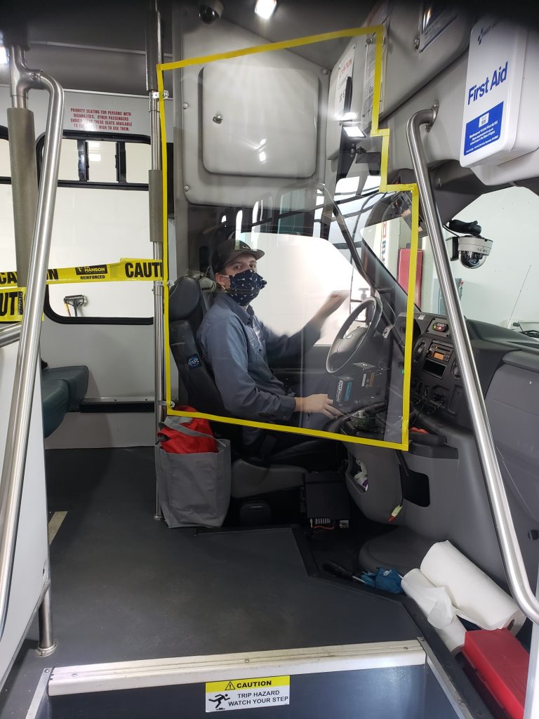 Bus Driver behind plastic shield wearing face mask